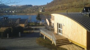 Een houten gebouw met een gebogen dak, met uitzicht op een meer en heuvels.