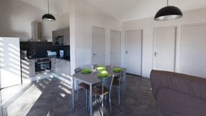 Een compacte keuken met moderne apparaten, een eethoek met tafel en stoelen, en een bank in een zithoek.