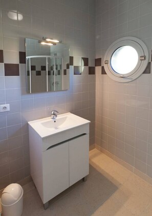 A bathroom with a white sink, a mirror, and a round window. - HOLIDAY VILLAGE OF LAKE MENET / FACING THE LAKE OF 14 HECTARES (Menet)