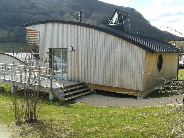 A wooden building with a sloped roof, a small porch, and a staircase leading to a door. - HOLIDAY VILLAGE OF LAKE MENET / FACING THE LAKE OF 14 HECTARES (Menet)