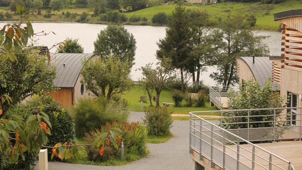 Propiedad frente al lago con cabañas de madera, un paseo cubierto y vistas al lago y la vegetación circundante.