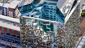 Ein modernes Gebäude mit einer einzigartigen, geometrischen Fassade, großen Fenstern und einem markanten Eingang.
