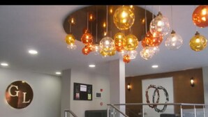 Eine großzügige Lobby mit einem modernen Kronleuchter, einem Empfangsschalter und einer Treppe mit Glasgeländern.
