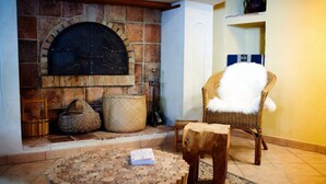 Una habitación acogedora con chimenea de piedra, muebles de mimbre y una pequeña mesa de madera.