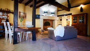 Una sala acogedora con chimenea, un comedor con mesa y sillas de madera, y un sofá.