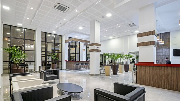 A spacious lobby with seating areas, a reception desk, and large windows. - Slim Guarapuava (Guarapuava)