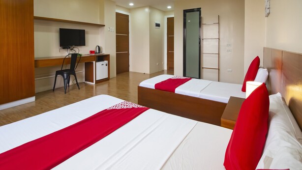 A hotel room with two beds, a desk, a chair, a television, and a wardrobe.