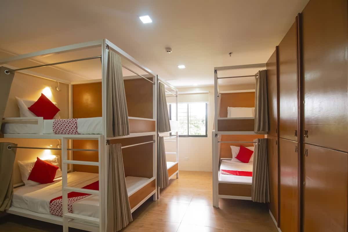A hotel room with bunk beds, wooden flooring, and a window.