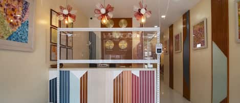 A hotel reception area with a modern design, including a reception desk, decorative lighting, and framed artwork on the walls.