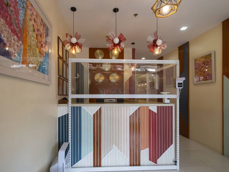 A reception area with a modern design, featuring a geometric patterned counter, decorative lighting, and clocks displaying time from London and New York.