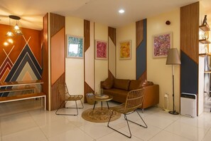 A modern living room with a sofa, two chairs, a coffee table, and a lamp. There are abstract paintings on the walls and a window. - Super OYO 832 The Teepee Place Hostel & Residence Inn (Cebu City)