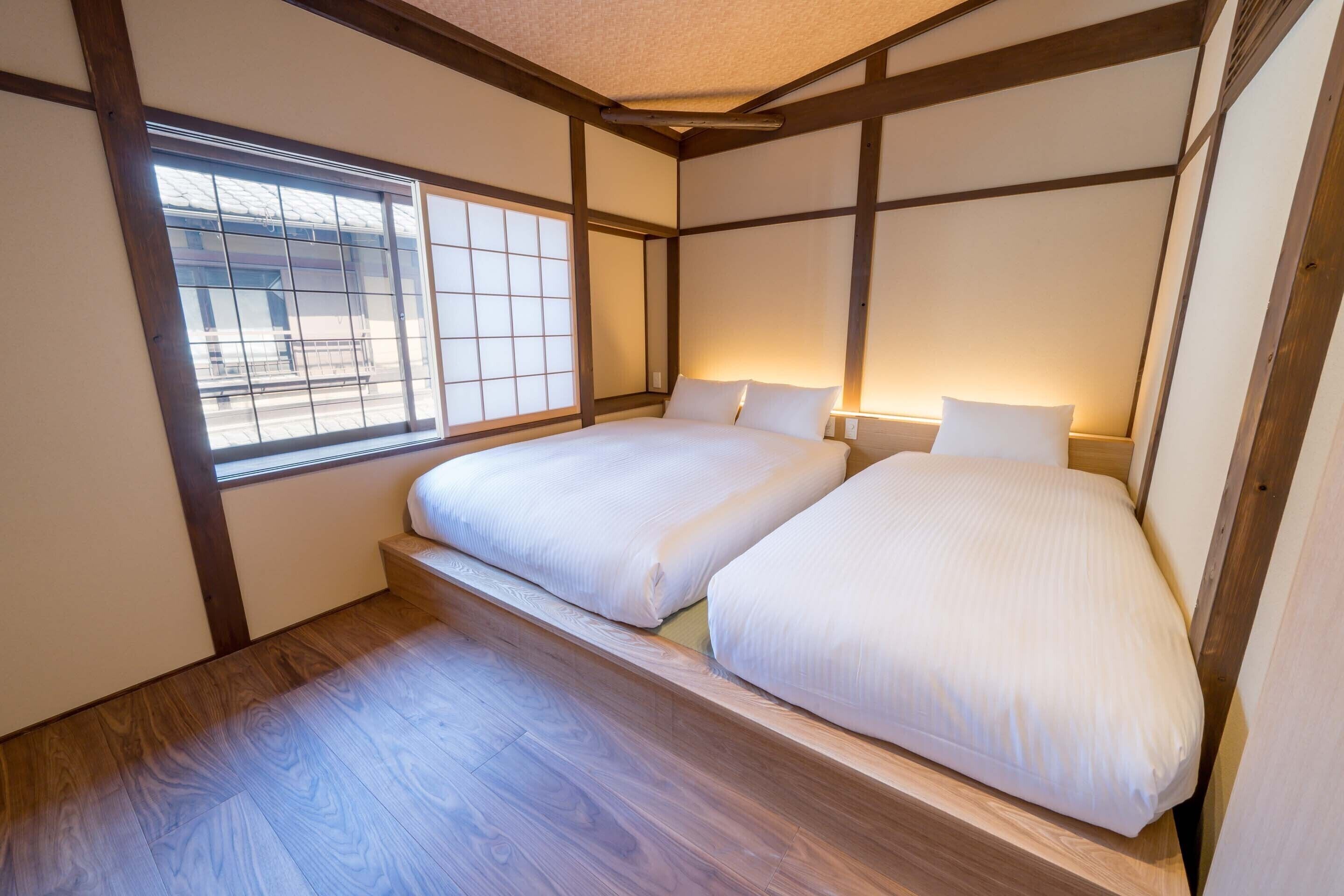 Ein traditionelles japanisches Schlafzimmer mit Tatami-Böden, einem niedrigen Plattformbett und verschiebbaren Shoji-Türen.