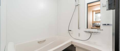 Un baño moderno con una bañera blanca, un cabezal de ducha de mano, un lavabo integrado y un espejo sobre el lavabo.