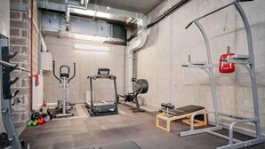 Un gimnasio con diverso equipamiento de ejercicio, incluyendo una banca, una estructura para sentadillas y una banca de pesas.
