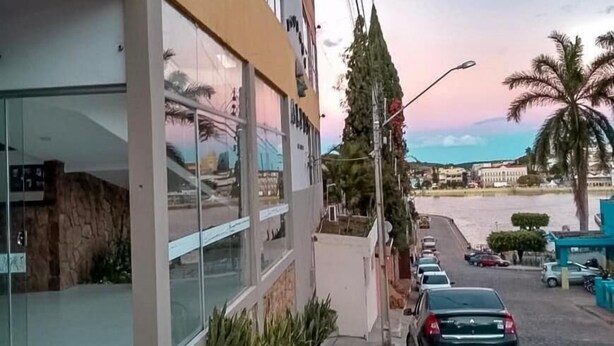 Un edificio moderno con grandes ventanales, fachada de piedra y un estacionamiento con coches.