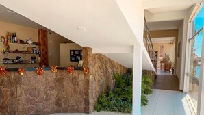 Amplio espacio interior con pared de piedra, suelo de baldosas y una escalera que sube a otro nivel.