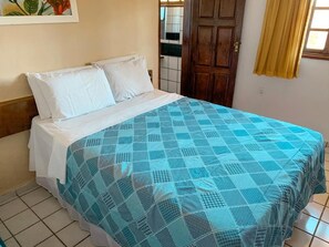 A bed with a blue patterned bedspread and white pillows, a wooden headboard, and a tiled floor. - Pousada Alpes de Triunfo (Triunfo)