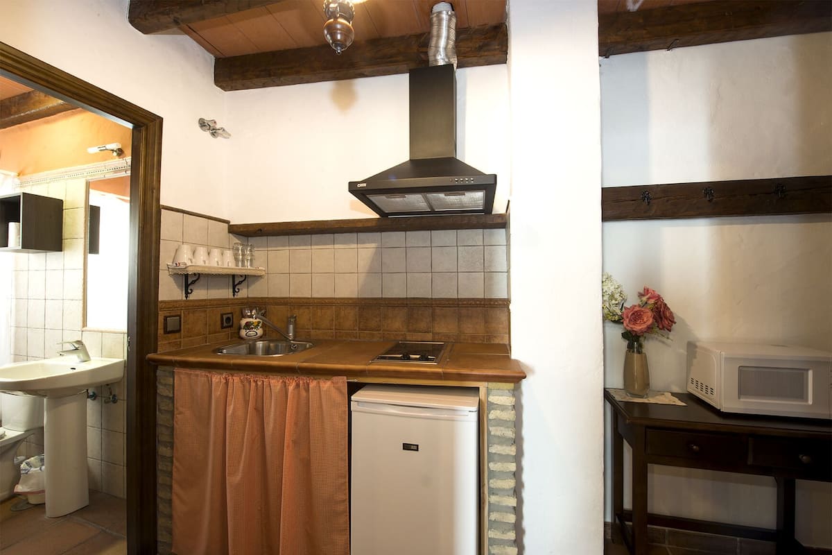 Uma cozinha compacta com forno embutido, pia e micro-ondas.