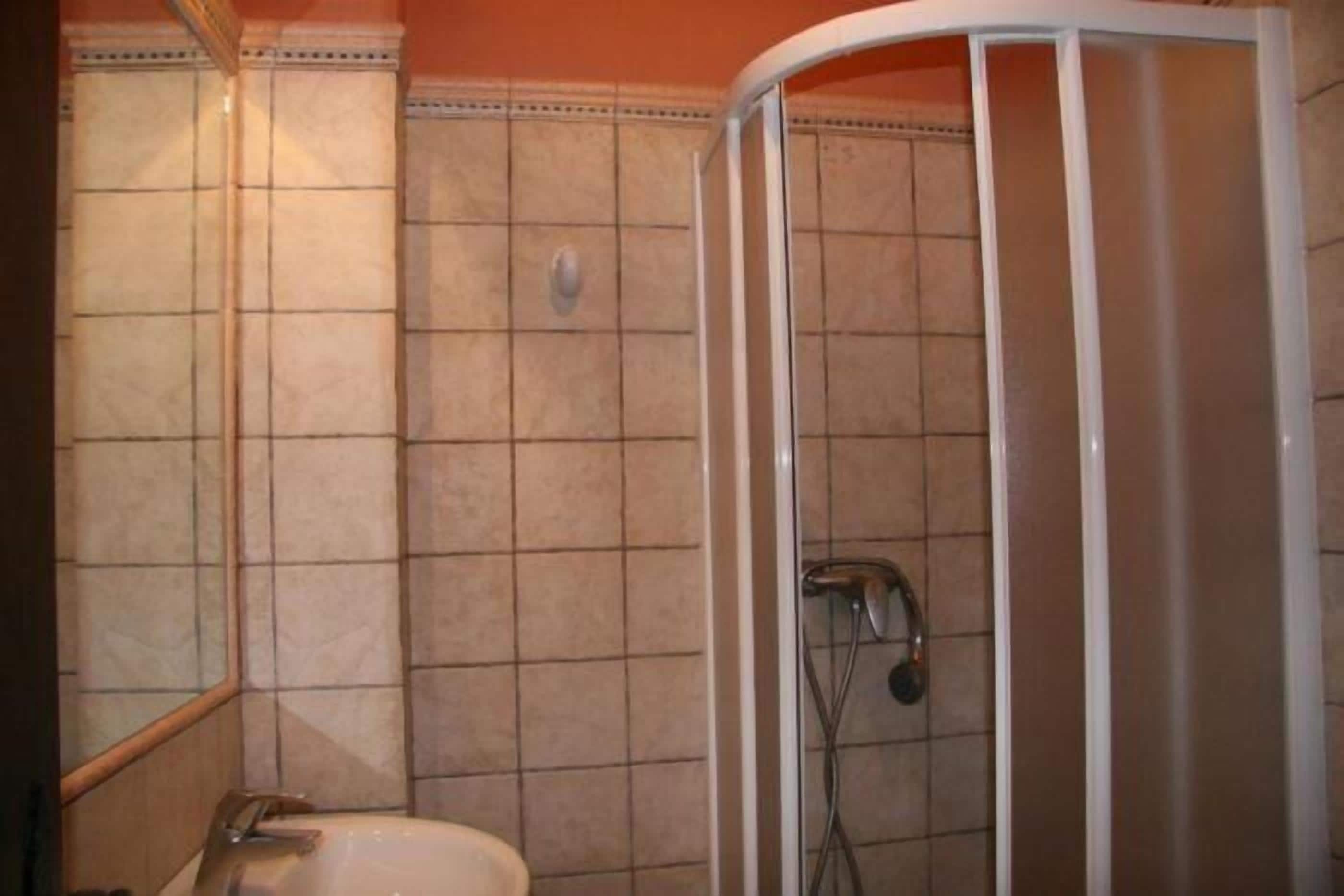 A bathroom with a shower, a sink, and tiled walls.