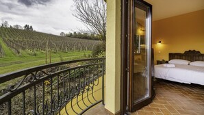 A hotel room with a balcony overlooking a vineyard.