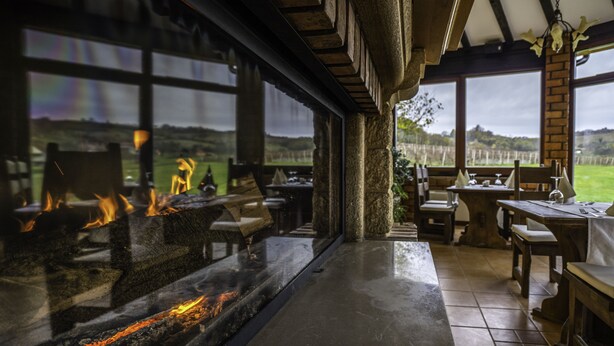 A cozy room with a fireplace, large windows, and a view of the countryside.