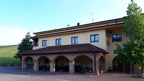 A building with a brick entrance and a tiled roof, surrounded by a paved area and greenery.