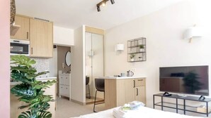 Una habitación de hotel moderna con cama, televisión, escritorio y kitchenette.