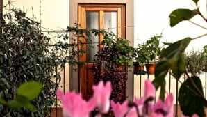 A building with a wooden door and a window, surrounded by greenery and plants.