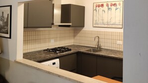 Una cocina pequeña con estufa a gas, un lavamanos y salpicadero de azulejos.