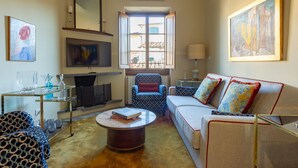 Una sala de estar con sofá, sillón, mesa de centro, televisor y obras de arte.