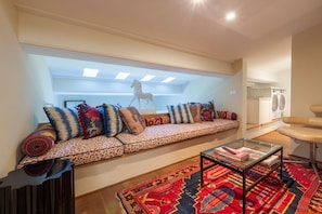Una sala de estar moderna con un conjunto de sofás, una mesa de centro de vidrio y una alfombra estampada.