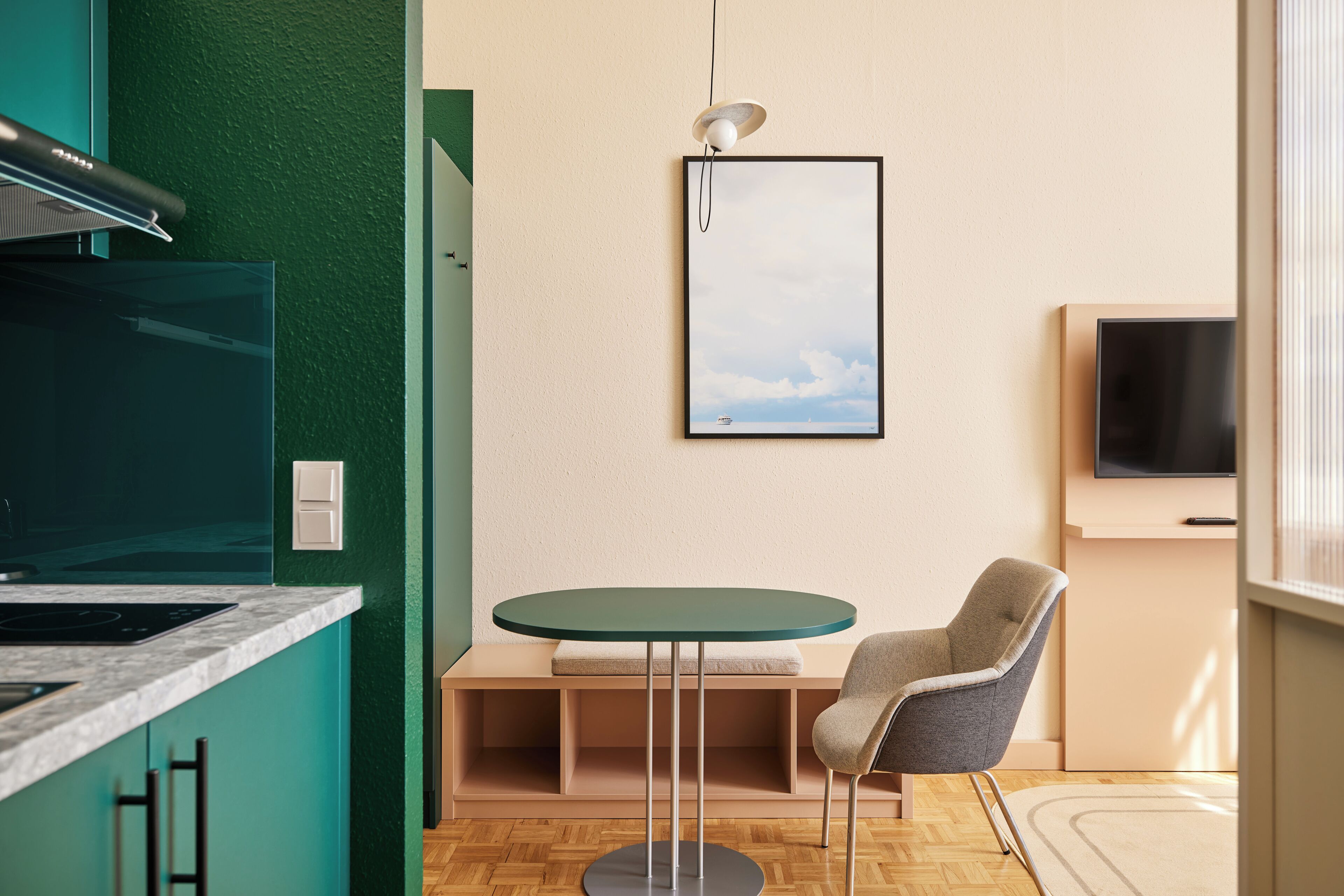 A modern kitchen with a built-in stove, a round table with a chair, and a framed picture on the wall.