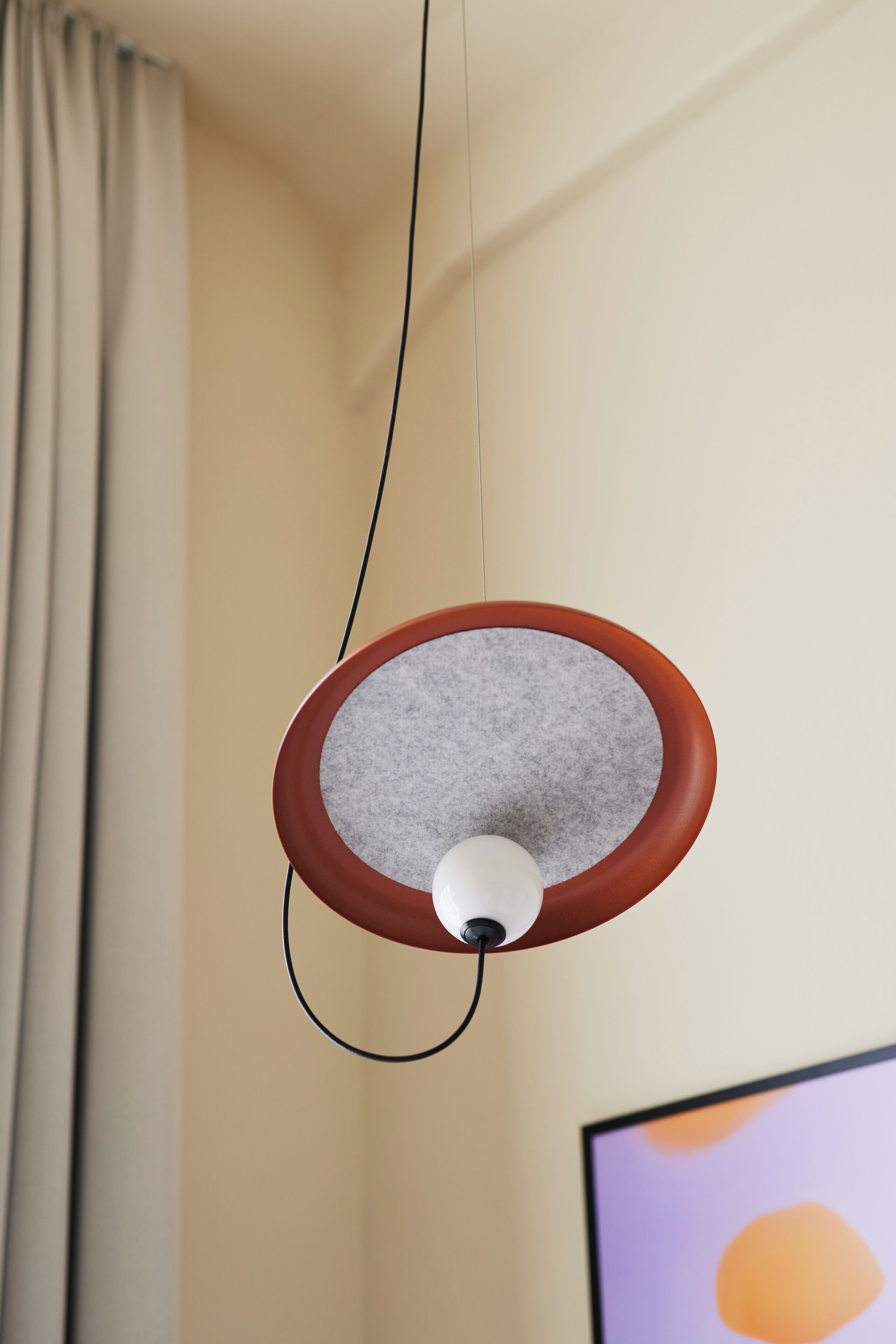 A pendant light with a circular shade and a white bulb, hanging from a cord.