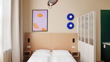 Ein Hotelzimmer mit Bett, Nachttischen, einer Wandleuchte, einem gerahmten Kunstwerk und einem Fenster mit Vorhängen.