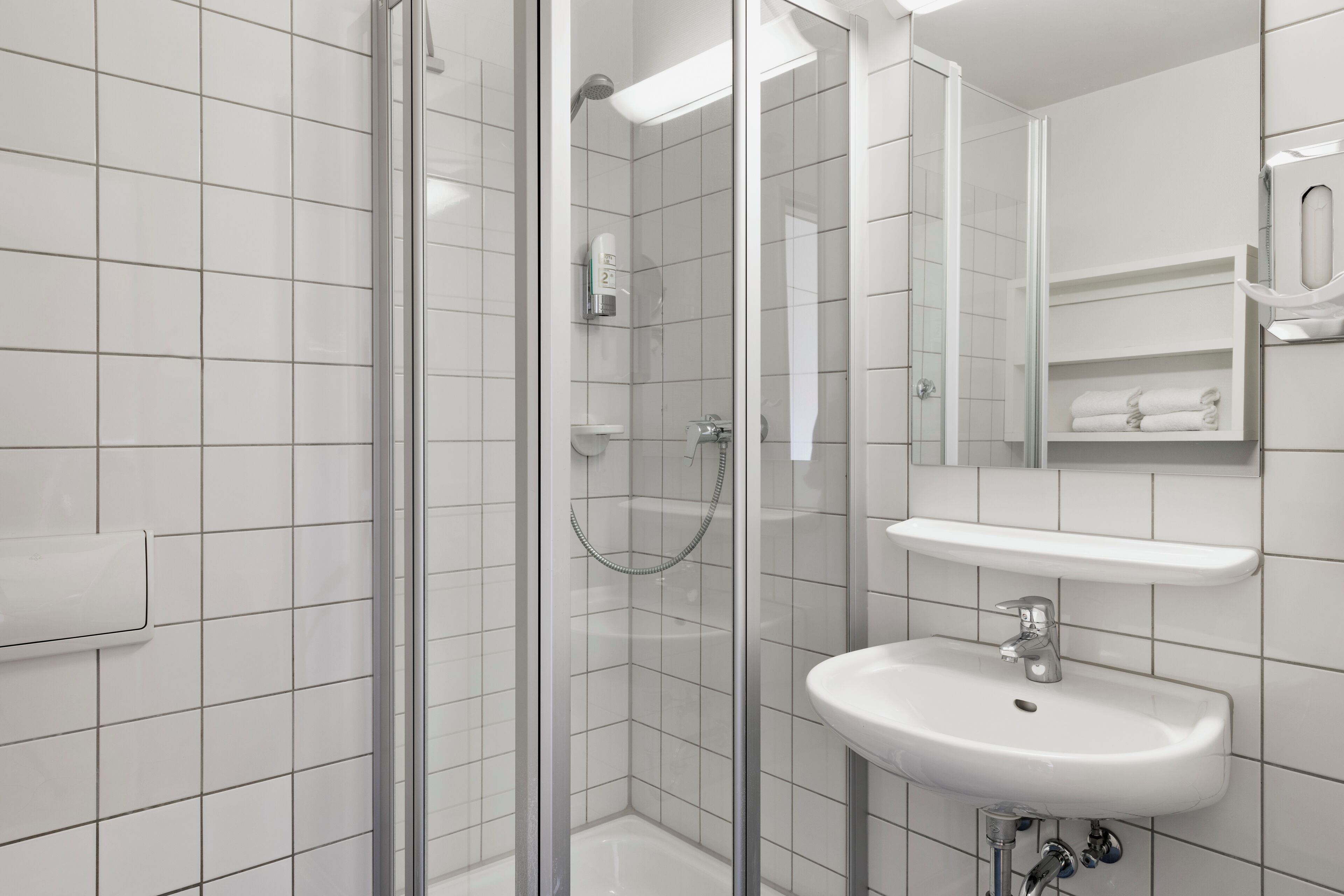 A modern bathroom with a glass-enclosed shower, a white sink, and a mirror above the sink.