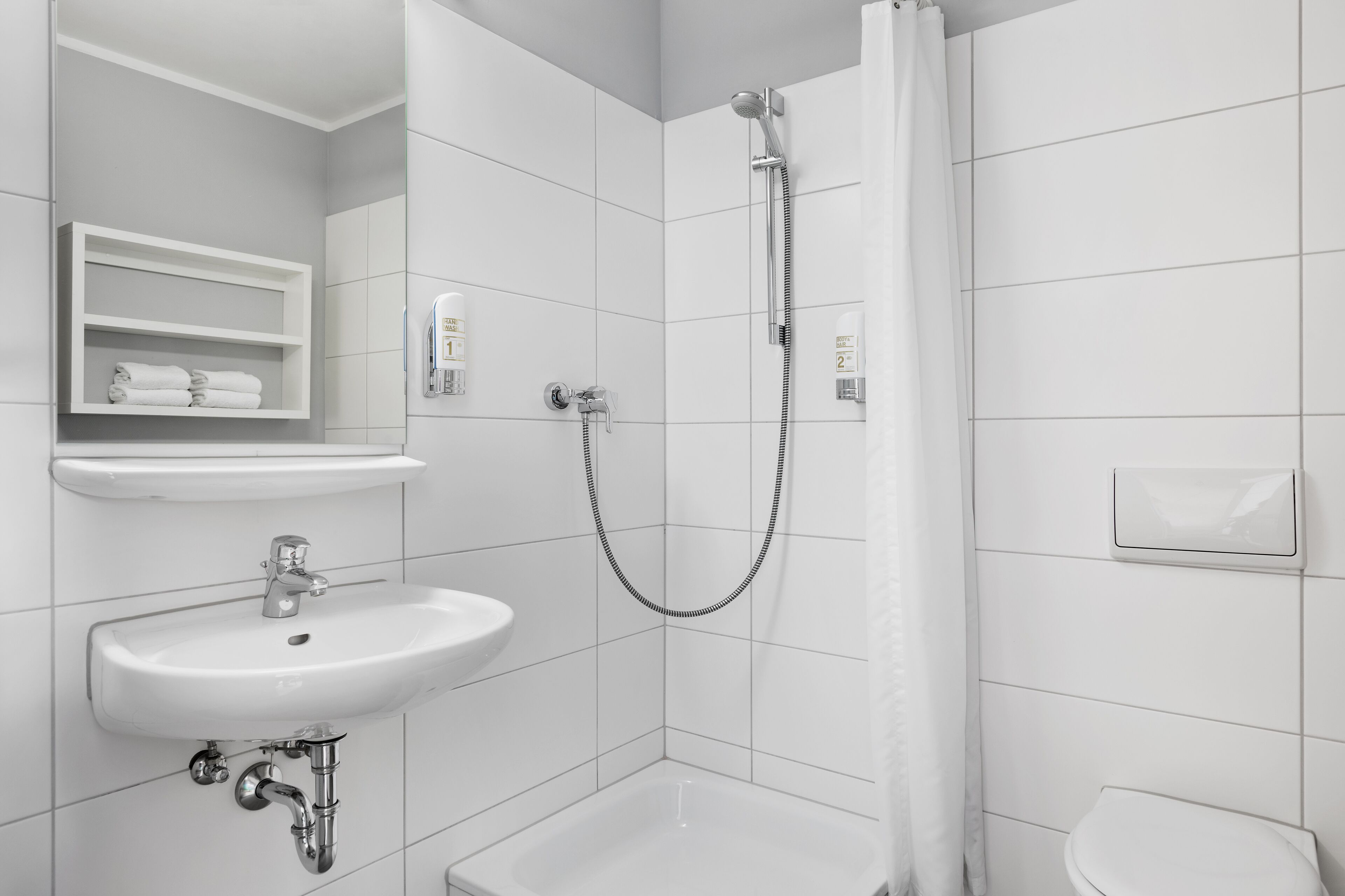 Un baño moderno con lavamanos, inodoro y ducha.