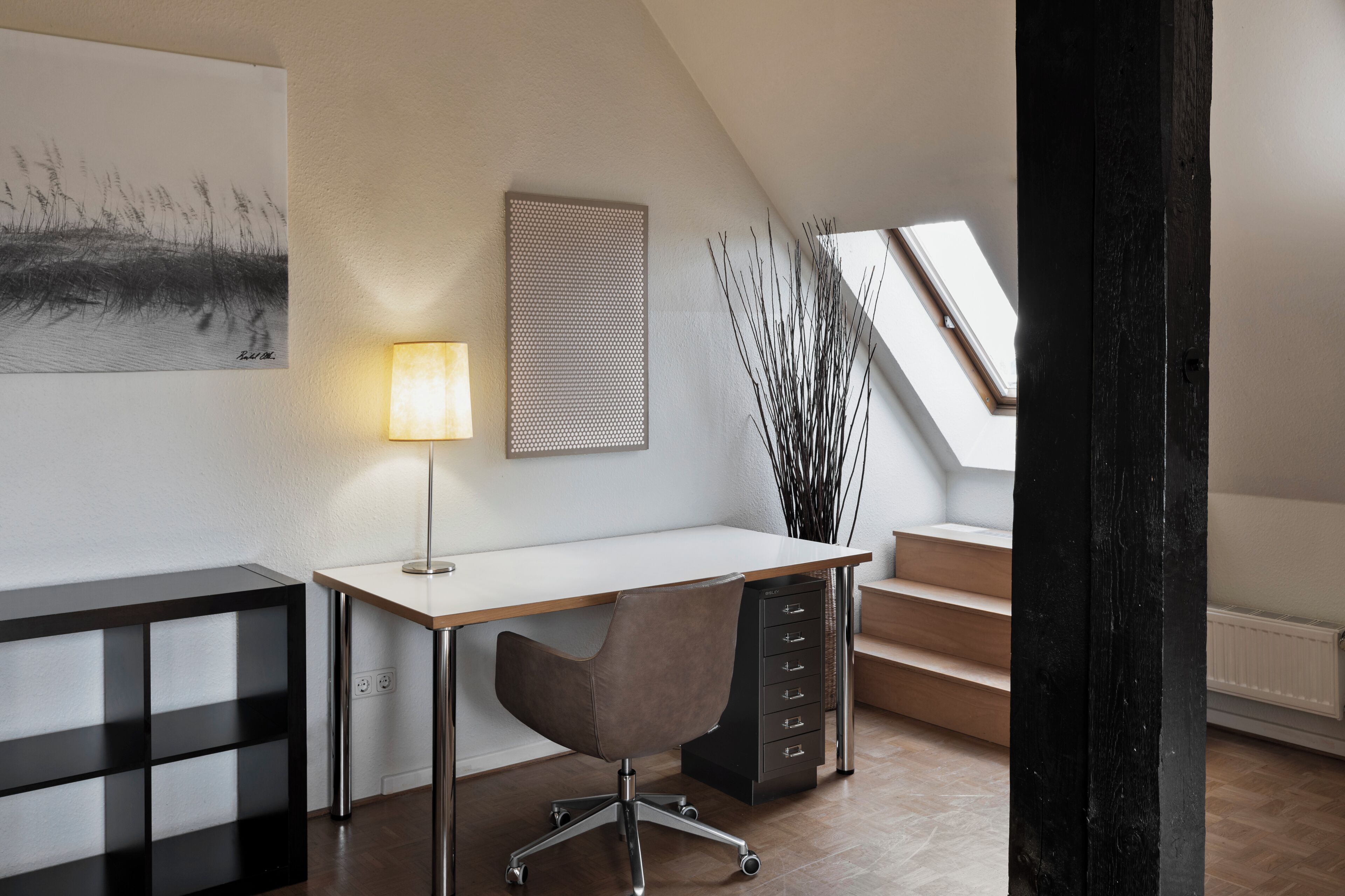 A modern office space with a desk, chair, and a lamp.