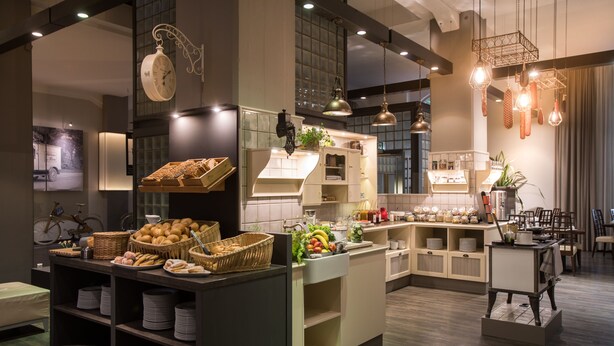 Una cocina moderna con una isla central, electrodomésticos integrados y lámparas colgantes.