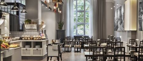 A modern dining area with wooden tables and chairs, a buffet counter, and a large window with curtains.