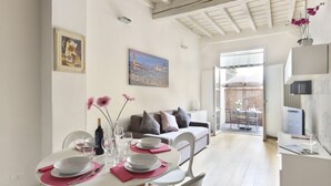 A dining area with a table set for four, a sofa, and a cityscape painting on the wall. - The Ginori  Apartment (Firenze)
