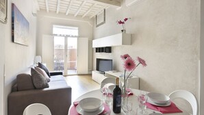 A modern living room with a sofa, dining table, and TV. - The Ginori  Apartment (Firenze)