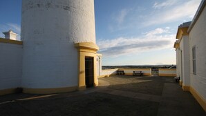 Un phare doté d’une cour dallée, d’un banc et offrant une vue sur la mer.