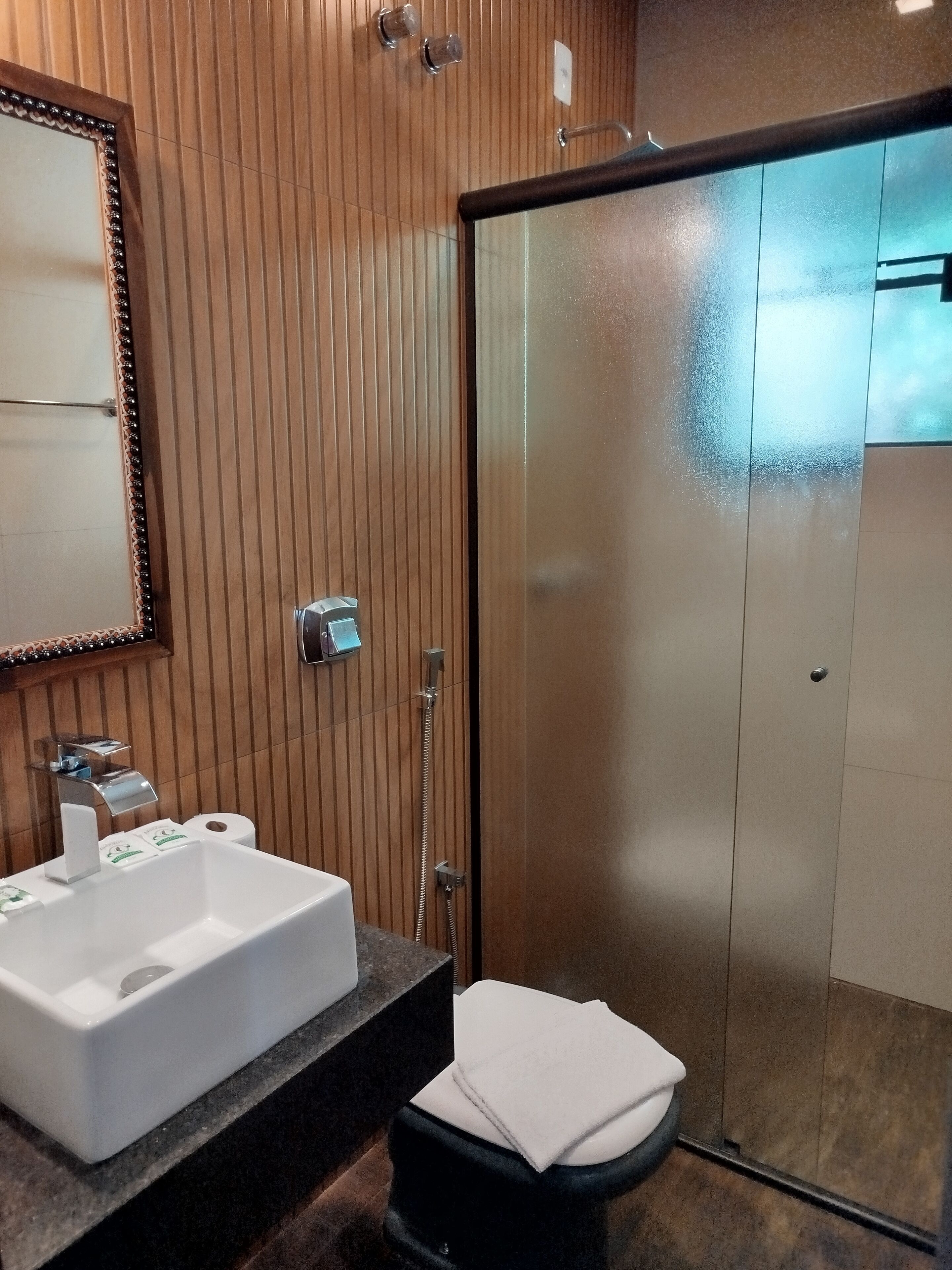 A bathroom with a white sink, a mirror, a towel, and a shower area.