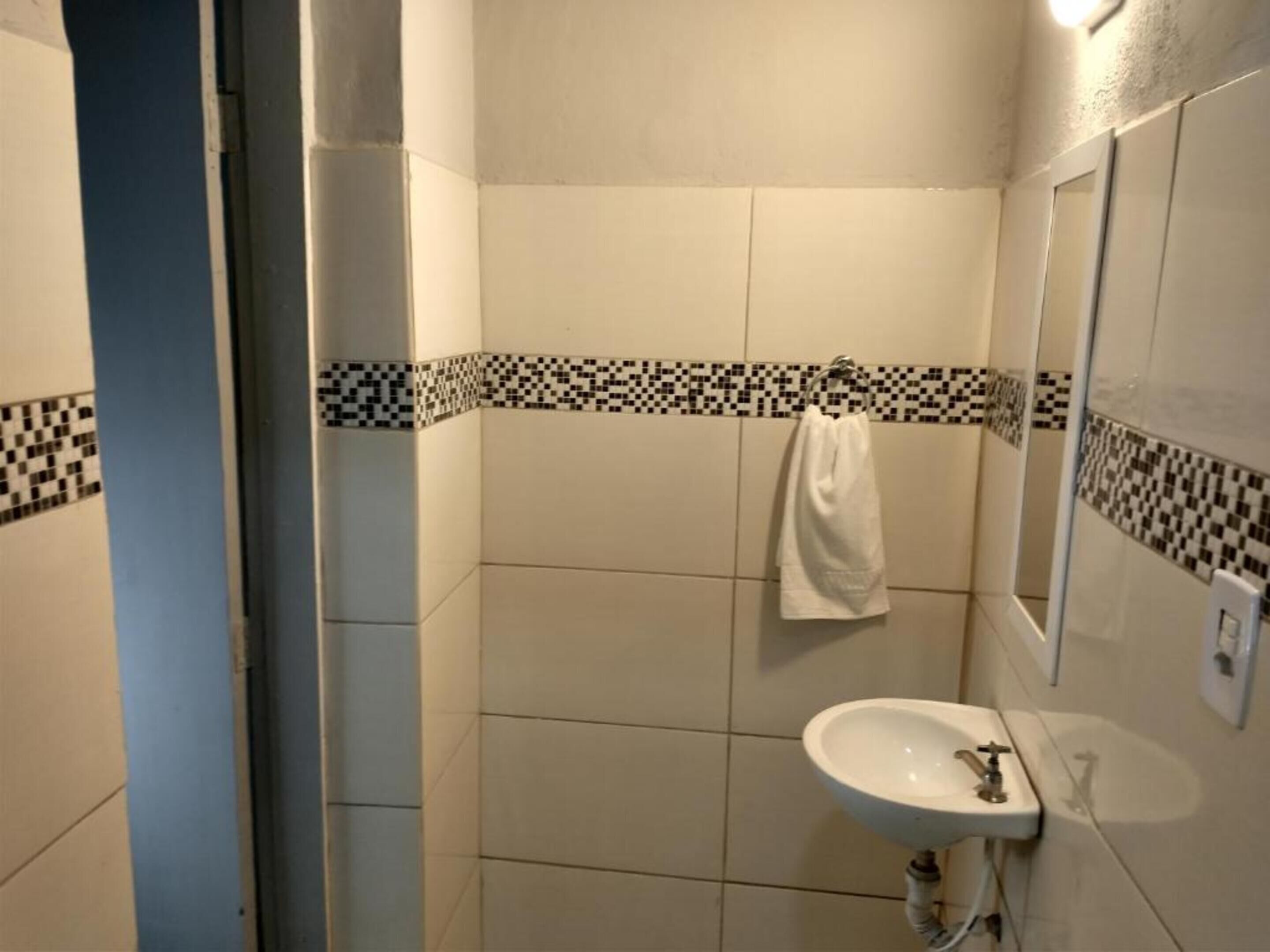 A bathroom with a white sink, a mirror, and a towel hanging on the wall.