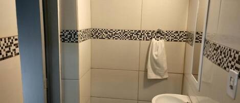 A bathroom with a white sink, a mirror, and a towel hanging on the wall.