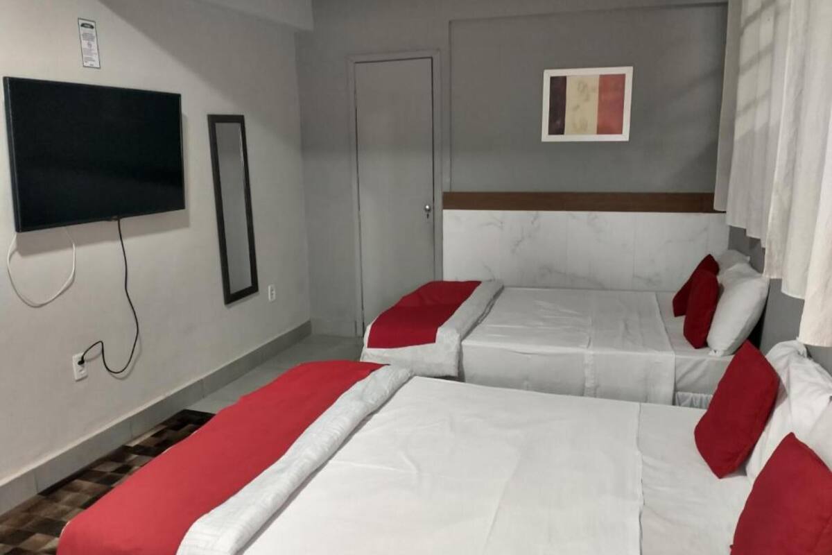 Habitación de hotel con dos camas, un televisor y una puerta.