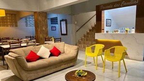 Un interior moderno con un sofá, dos sillones amarillos, una mesita redonda y una recepción.