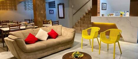 A modern interior with a sofa, two yellow chairs, a small round table, and a reception desk.