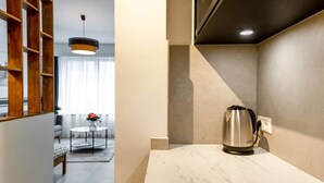 A modern kitchen with a marble countertop, a stainless steel kettle, and a wooden shelving unit. - Studio Sarah 4* super central near Sofitel (Luxembourg)