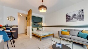 A modern apartment with a bed, sofa, and dining area. - Studio Sarah 4* super central near Sofitel (Luxembourg)
